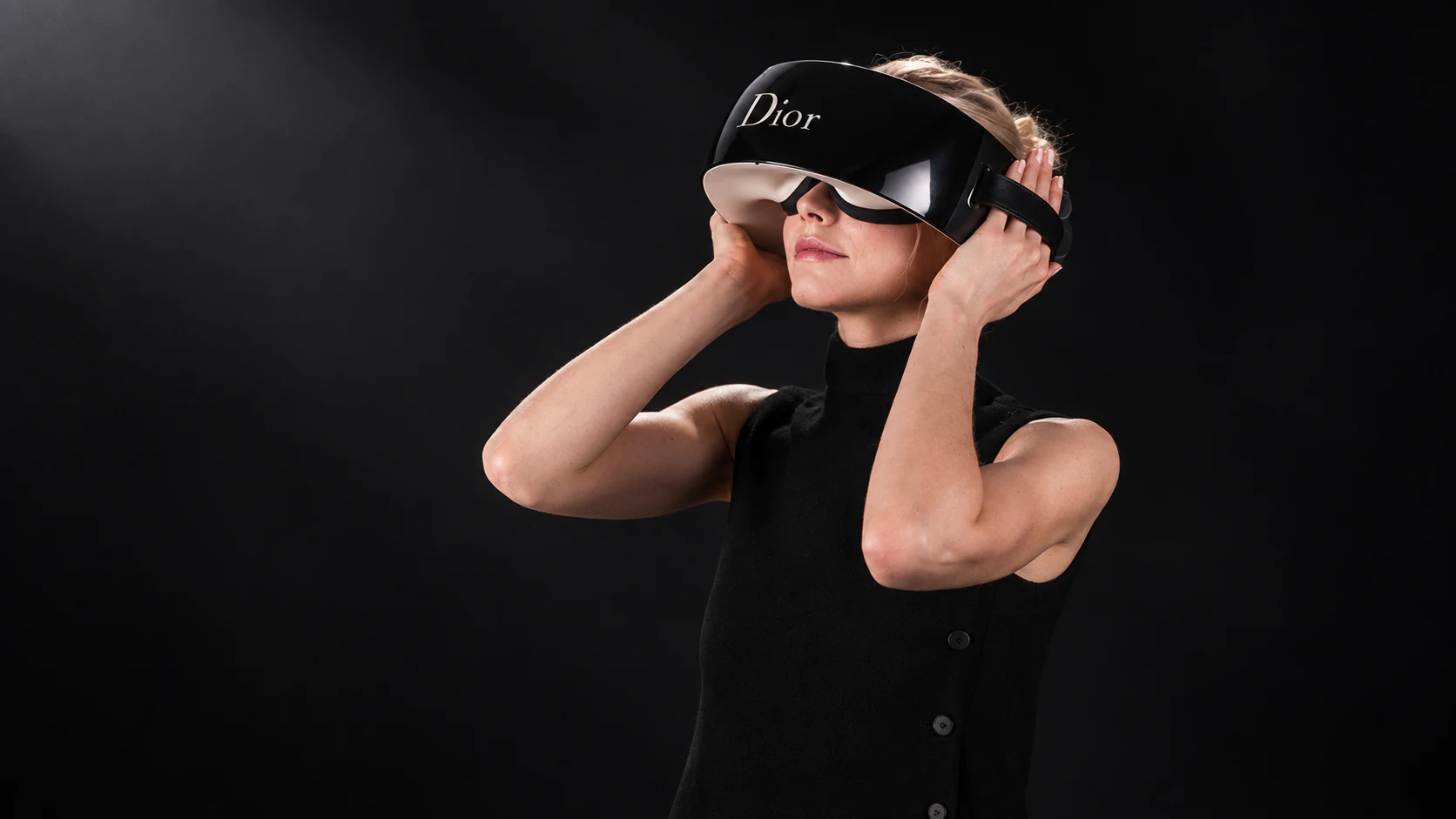 A woman dressed in black wearing the Dior Eyes virtual reality headset
