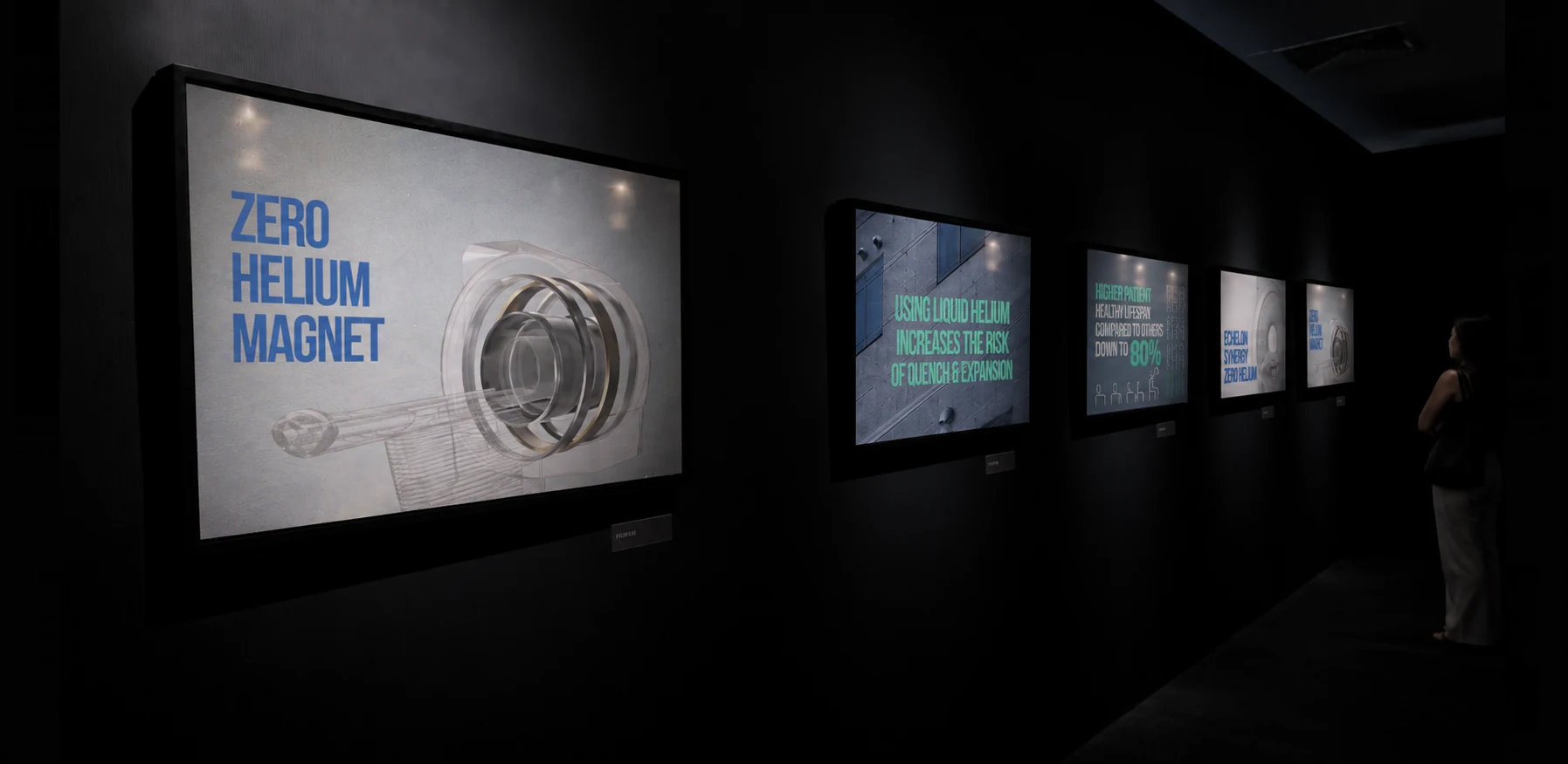 A dark Fujifilm exhibition gallery with five illuminated medical-imaging campaign screens
