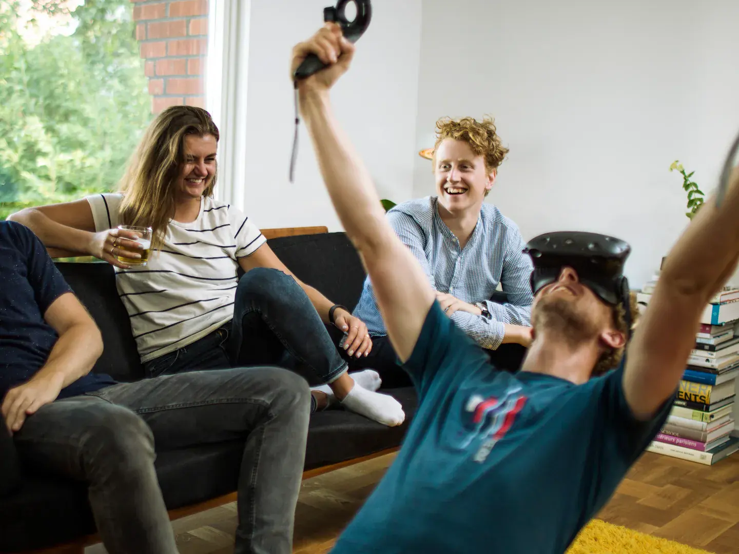 Friends laughing while a seated player tries Limberjack with a VR headset and motion controllers