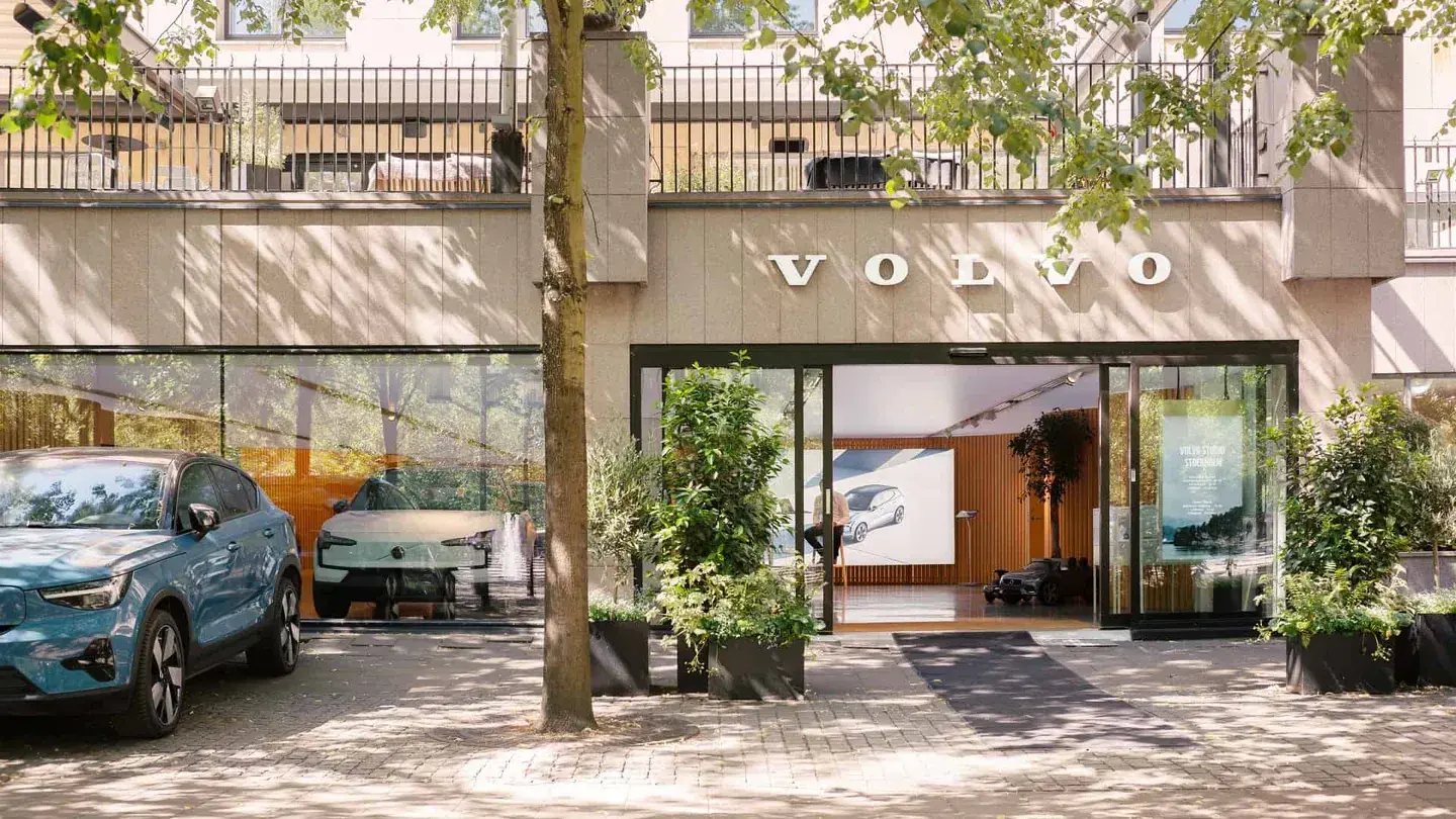 A Volvo Studio Store entrance framed by trees and parked cars